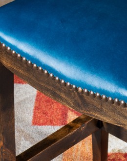 An image showcasing the Levi Saddle Stool, a masterpiece of American craftsmanship. The stool features a denim blue aniline dyed full grain leather seat, lightly sanded for a distressed look. Its clean-lined design boasts solid Alder Wood straight legs, r