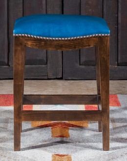 An image showcasing the Levi Saddle Stool, a masterpiece of American craftsmanship. The stool features a denim blue aniline dyed full grain leather seat, lightly sanded for a distressed look. Its clean-lined design boasts solid Alder Wood straight legs, r
