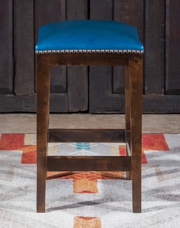 An image showcasing the Levi Saddle Stool, a masterpiece of American craftsmanship. The stool features a denim blue aniline dyed full grain leather seat, lightly sanded for a distressed look. Its clean-lined design boasts solid Alder Wood straight legs, r