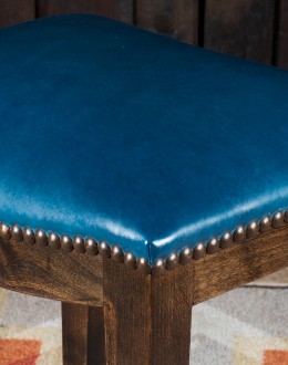 An image showcasing the Levi Saddle Stool, a masterpiece of American craftsmanship. The stool features a denim blue aniline dyed full grain leather seat, lightly sanded for a distressed look. Its clean-lined design boasts solid Alder Wood straight legs, r