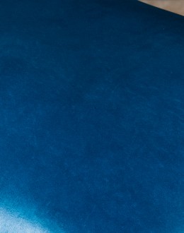 An image showcasing the Levi Saddle Stool, a masterpiece of American craftsmanship. The stool features a denim blue aniline dyed full grain leather seat, lightly sanded for a distressed look. Its clean-lined design boasts solid Alder Wood straight legs, r