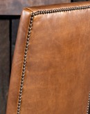 Sundance Saddle Leather Dining Chair featuring solid American Alder Wood frame with black walnut finish, saddle tan leather upholstery, brass nail tacks, and boot stitch emblem.