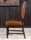 Sundance Saddle Leather Dining Chair featuring solid American Alder Wood frame with black walnut finish, saddle tan leather upholstery, brass nail tacks, and boot stitch emblem.