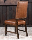 Sundance Saddle Leather Dining Chair featuring solid American Alder Wood frame with black walnut finish, saddle tan leather upholstery, brass nail tacks, and boot stitch emblem.