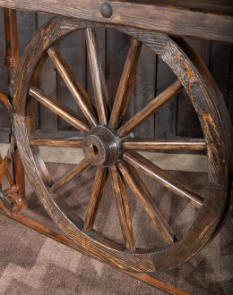 Western-style Pioneer Wagon Wheel Pub Table featuring a solid hand-forged iron base with a detailed wagon wheel design, finished in natural rust and sealed for durability. The top is crafted from distressed Chilean Pine, adding rustic elegance to the piec