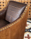 distressed brown leather chair with boot stitch emblem on seat back