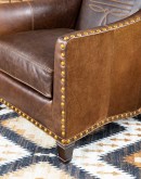 distressed brown leather chair with boot stitch emblem on seat back