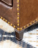 distressed brown leather chair with boot stitch emblem on seat back