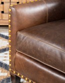 distressed brown leather chair with boot stitch emblem on seat back