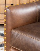 distressed brown leather chair with boot stitch emblem on seat back