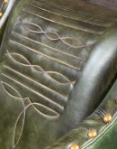 distressed olive color leather chair with boot stitch emblem on seat back