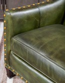 distressed olive color leather chair with boot stitch emblem on seat back