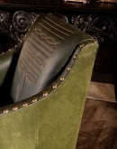 distressed olive color leather chair with boot stitch emblem on seat back