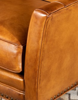distressed brown leather chair with native American inspired stitch emblem on seat back