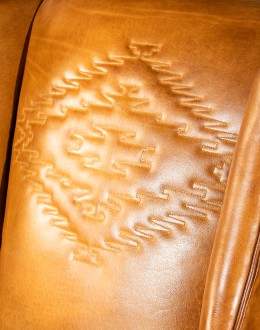distressed brown leather chair with native American inspired stitch emblem on seat back
