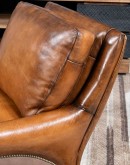 The Cowboy AF Leather Chair is a western-style armchair with a luxurious full-grain leather finish, hand-burnished leather details, and brushed sueded leather accents on the out arms. The chair features plush seat and back cushions, nickel nail trim, and