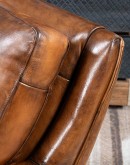 The Cowboy AF Leather Chair is a western-style armchair with a luxurious full-grain leather finish, hand-burnished leather details, and brushed sueded leather accents on the out arms. The chair features plush seat and back cushions, nickel nail trim, and