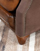 The Cowboy AF Leather Chair is a western-style armchair with a luxurious full-grain leather finish, hand-burnished leather details, and brushed sueded leather accents on the out arms. The chair features plush seat and back cushions, nickel nail trim, and