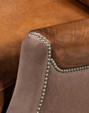 The Cowboy AF Leather Chair is a western-style armchair with a luxurious full-grain leather finish, hand-burnished leather details, and brushed sueded leather accents on the out arms. The chair features plush seat and back cushions, nickel nail trim, and