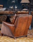 The Cowboy AF Leather Chair is a western-style armchair with a luxurious full-grain leather finish, hand-burnished leather details, and brushed sueded leather accents on the out arms. The chair features plush seat and back cushions, nickel nail trim, and