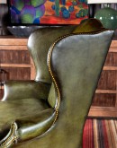 American-made Gentry Olive Wingback Chair with hand-brushed olive green leather, gold nail tack detailing, and a sturdy hardwood frame.
