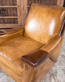 A luxurious Lucky Leather Chair featuring a rich tan full-grain leather upholstery, contrasting leather accents on the arms, brass nail tacks, and a unique leather horseshoe detail.