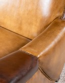 A luxurious Lucky Leather Chair featuring a rich tan full-grain leather upholstery, contrasting leather accents on the arms, brass nail tacks, and a unique leather horseshoe detail.