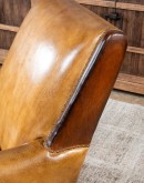 A luxurious Lucky Leather Chair featuring a rich tan full-grain leather upholstery, contrasting leather accents on the arms, brass nail tacks, and a unique leather horseshoe detail.