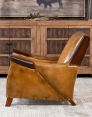 A luxurious Lucky Leather Chair featuring a rich tan full-grain leather upholstery, contrasting leather accents on the arms, brass nail tacks, and a unique leather horseshoe detail.