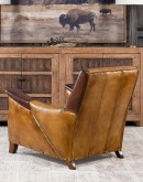 A luxurious Lucky Leather Chair featuring a rich tan full-grain leather upholstery, contrasting leather accents on the arms, brass nail tacks, and a unique leather horseshoe detail.