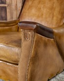 A luxurious Lucky Leather Chair featuring a rich tan full-grain leather upholstery, contrasting leather accents on the arms, brass nail tacks, and a unique leather horseshoe detail.