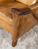 A luxurious Lucky Leather Chair featuring a rich tan full-grain leather upholstery, contrasting leather accents on the arms, brass nail tacks, and a unique leather horseshoe detail.