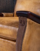 A luxurious Lucky Leather Chair featuring a rich tan full-grain leather upholstery, contrasting leather accents on the arms, brass nail tacks, and a unique leather horseshoe detail.