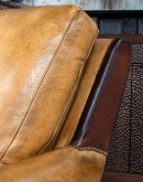 A luxurious Lucky Leather Chair featuring a rich tan full-grain leather upholstery, contrasting leather accents on the arms, brass nail tacks, and a unique leather horseshoe detail.