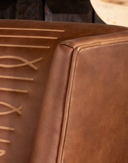 distressed brown leather chair with boot stitch emblem on seat back