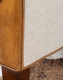 Image of the American-made Polo Club Chair showcasing its full grain leather upholstery with hand burnished details, and luxurious cream nylon tweed-textured fabric wrapping the outside arms and back, signifying modern rustic elegance