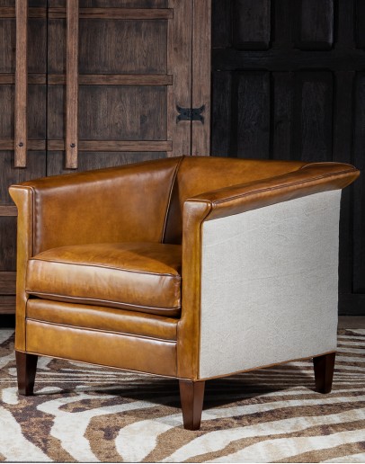 Image of the American-made Polo Club Chair showcasing its full grain leather upholstery with hand burnished details, and luxurious cream nylon tweed-textured fabric wrapping the outside arms and back, signifying modern rustic elegance