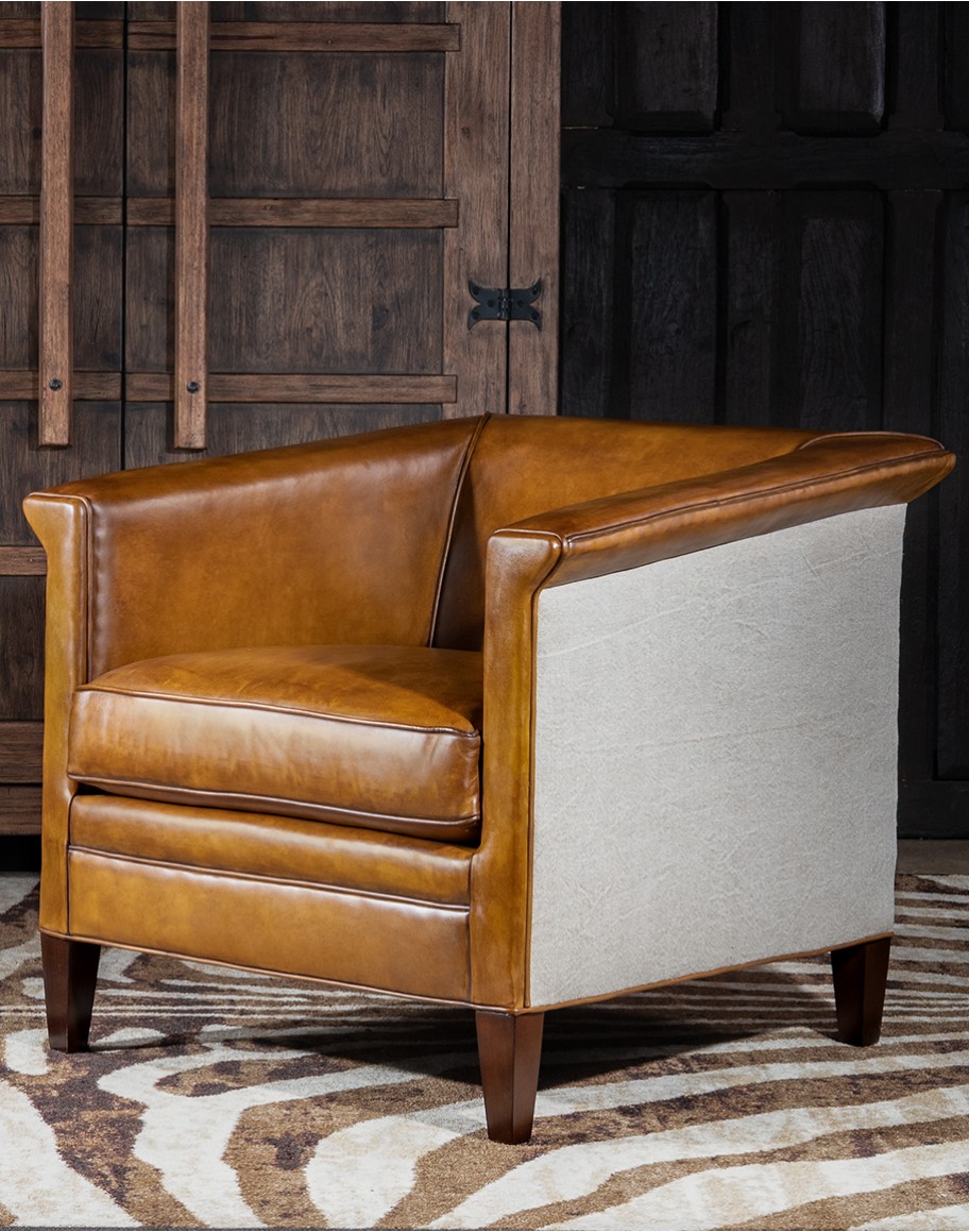 Image of the American-made Polo Club Chair showcasing its full grain leather upholstery with hand burnished details, and luxurious cream nylon tweed-textured fabric wrapping the outside arms and back, signifying modern rustic elegance