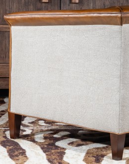 Image of the American-made Polo Club Chair showcasing its full grain leather upholstery with hand burnished details, and luxurious cream nylon tweed-textured fabric wrapping the outside arms and back, signifying modern rustic elegance