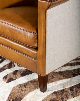 Image of the American-made Polo Club Chair showcasing its full grain leather upholstery with hand burnished details, and luxurious cream nylon tweed-textured fabric wrapping the outside arms and back, signifying modern rustic elegance