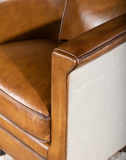Image of the American-made Polo Club Chair showcasing its full grain leather upholstery with hand burnished details, and luxurious cream nylon tweed-textured fabric wrapping the outside arms and back, signifying modern rustic elegance