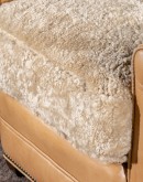 Introducing the Tulip Club Chair - a beautifully designed, American-made chair that's sure to elevate any living space! This image showcases the chair's stunning palomino-colored, full-grain leather and the cream shearling hide seat cushion, which provide