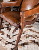 The Yachtsman's Leather Chair is a stunning piece of furniture designed with a modern rustic aesthetic. The chair features a solid black walnut frame and armrests wrapped in thick true saddle leather. The leather is a full grain hide with hand burnished d