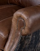 The Bronco Brindleback Recliner: A masterfully crafted, American-made recliner with a grand scale, bustle back, and supple light brown leather. Upholstery-grade brindle cowhide and gold-colored nail tacks add a touch of Western charm. Experience ultimate