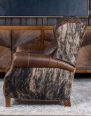 The Bronco Brindleback Recliner: A masterfully crafted, American-made recliner with a grand scale, bustle back, and supple light brown leather. Upholstery-grade brindle cowhide and gold-colored nail tacks add a touch of Western charm. Experience ultimate