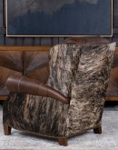 The Bronco Brindleback Recliner: A masterfully crafted, American-made recliner with a grand scale, bustle back, and supple light brown leather. Upholstery-grade brindle cowhide and gold-colored nail tacks add a touch of Western charm. Experience ultimate