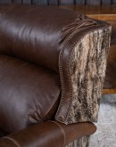 The Bronco Brindleback Recliner: A masterfully crafted, American-made recliner with a grand scale, bustle back, and supple light brown leather. Upholstery-grade brindle cowhide and gold-colored nail tacks add a touch of Western charm. Experience ultimate