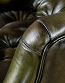 distressed olive green leather recliner with button tufting on seat and back