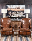 A brown leather recliner chair with a wooden base and armrests is pictured against a plain beige background. The chair has a tight back with a boot stitch emblem and is adorned with premium upholstery grade brindle cowhide on the sides and outside back. T