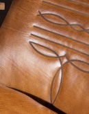 western style leather barrel chair with brindle cowhide on the outside and boot stitch emblem on the seatback.